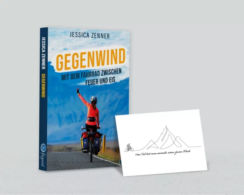 Buch "Gegenwind" neben der Postkarte "Fahrradfahrer vor Berg"